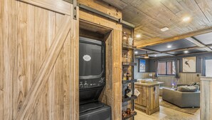 Une cuisine rustique dotée d’un four encastré, d’étagères en bois et d’un coin salon accueillant.
