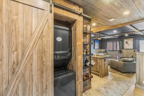 Une cuisine rustique dotée d’un four encastré, d’étagères en bois et d’un coin salon accueillant.