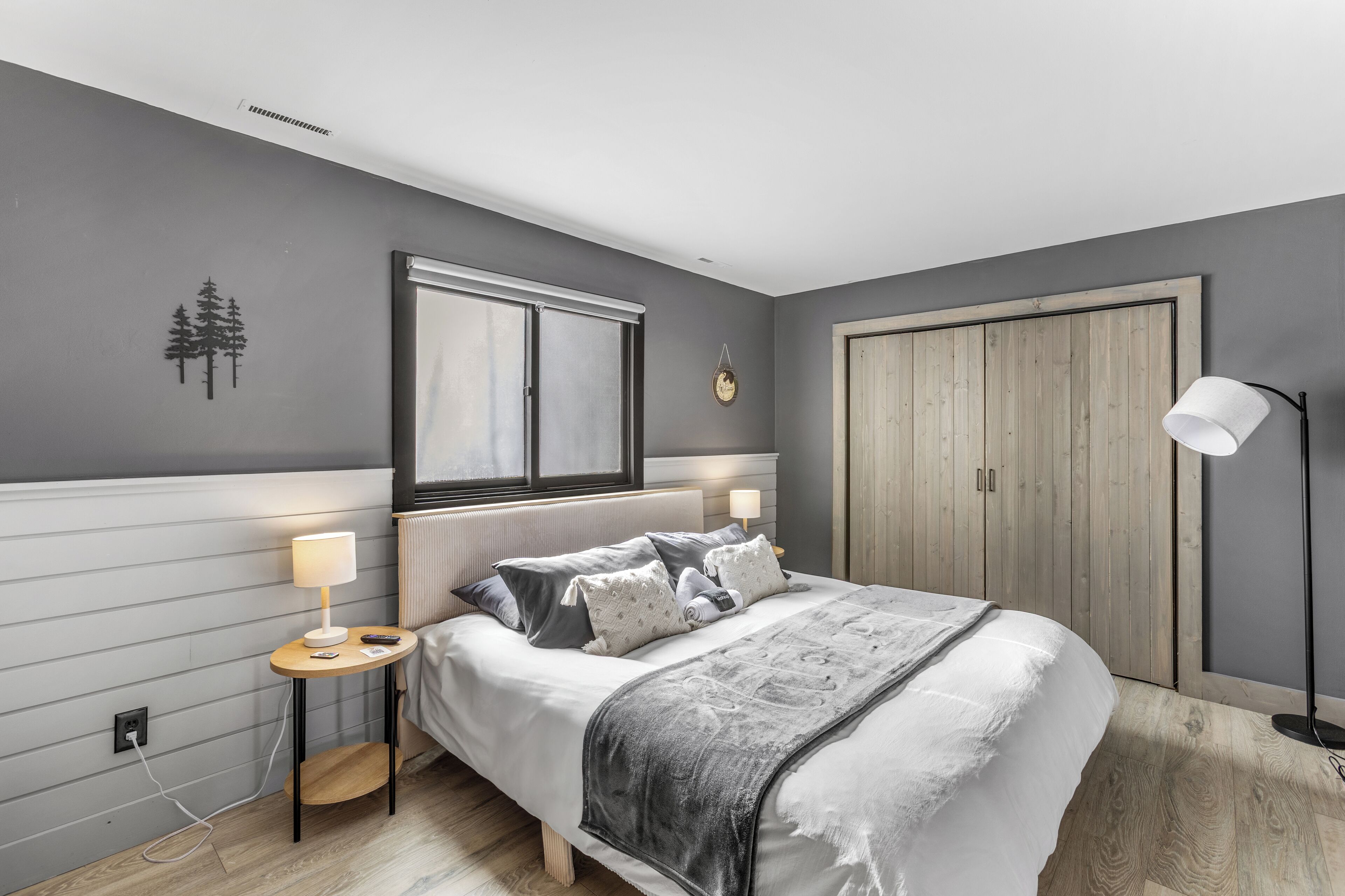 Un dormitorio con cama, mesitas de noche, un armario y una ventana.