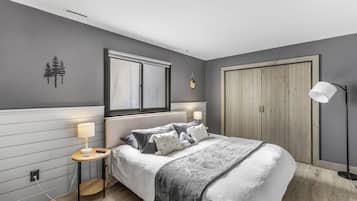 Un dormitorio con cama, mesitas de noche, un armario y una ventana.