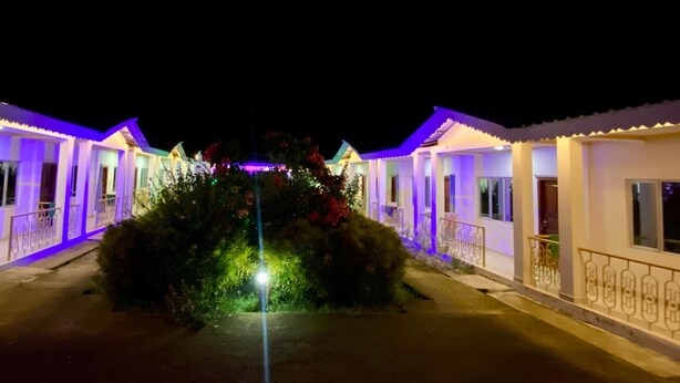 Une rangée de bâtiments de style traditionnel, avec un jardin central illuminé de lumières violettes et vertes.