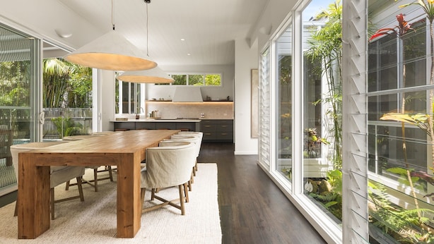 Een moderne keuken met een centraal eiland, grote ramen en uitzicht op groen.