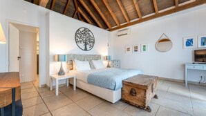 Een slaapkamer met een bed, nachtkastjes, een houten kist, een bureau en kunstwerken aan de wanden.