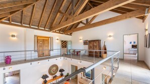 Een ruime loft met zichtbare houten balken, een balkon met een hekwerk en uitzicht op het interieur.