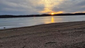 Une vaste étendue d’eau à ciel ouvert, avec un coucher de soleil à l’horizon.