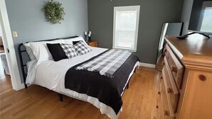 Une chambre à coucher avec un lit, une commode en bois et un ventilateur de plafond.