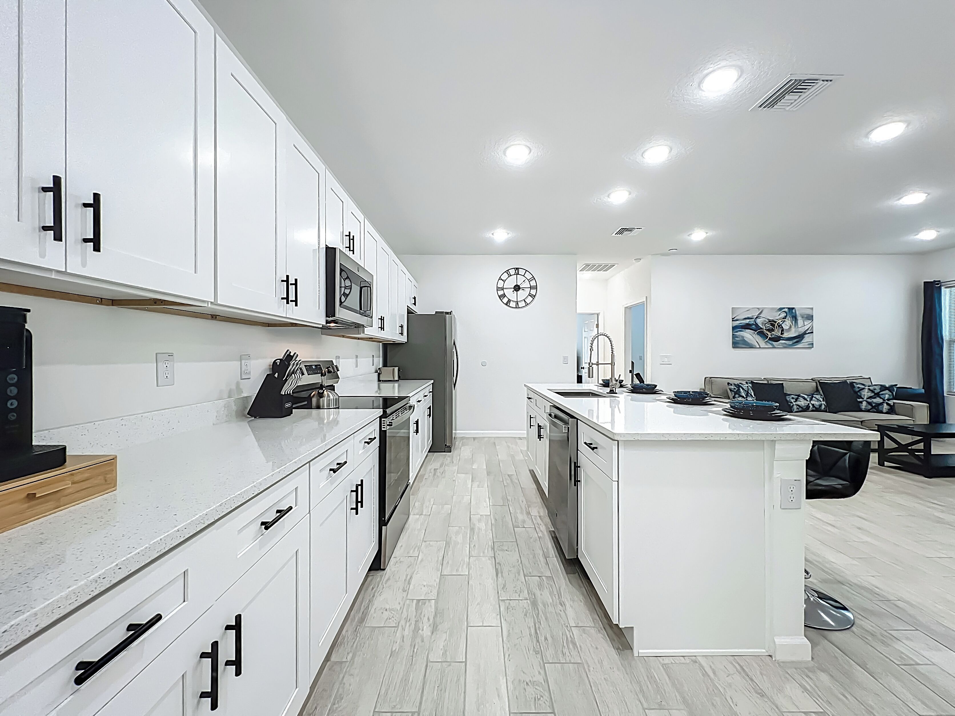 A modern kitchen with white cabinetry, a central island, and a microwave above the counter.