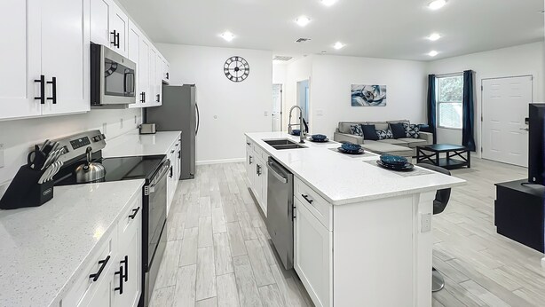 A modern kitchen with white cabinetry, stainless steel appliances, and a central island with a sink. - Getaways, your way!
Spacious & Modern 3BR, 2BA (Sanford)