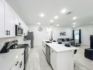 A modern kitchen with white cabinetry, stainless steel appliances, and a central island with a sink. - Getaways, your way!
Spacious & Modern 3BR, 2BA (Sanford)