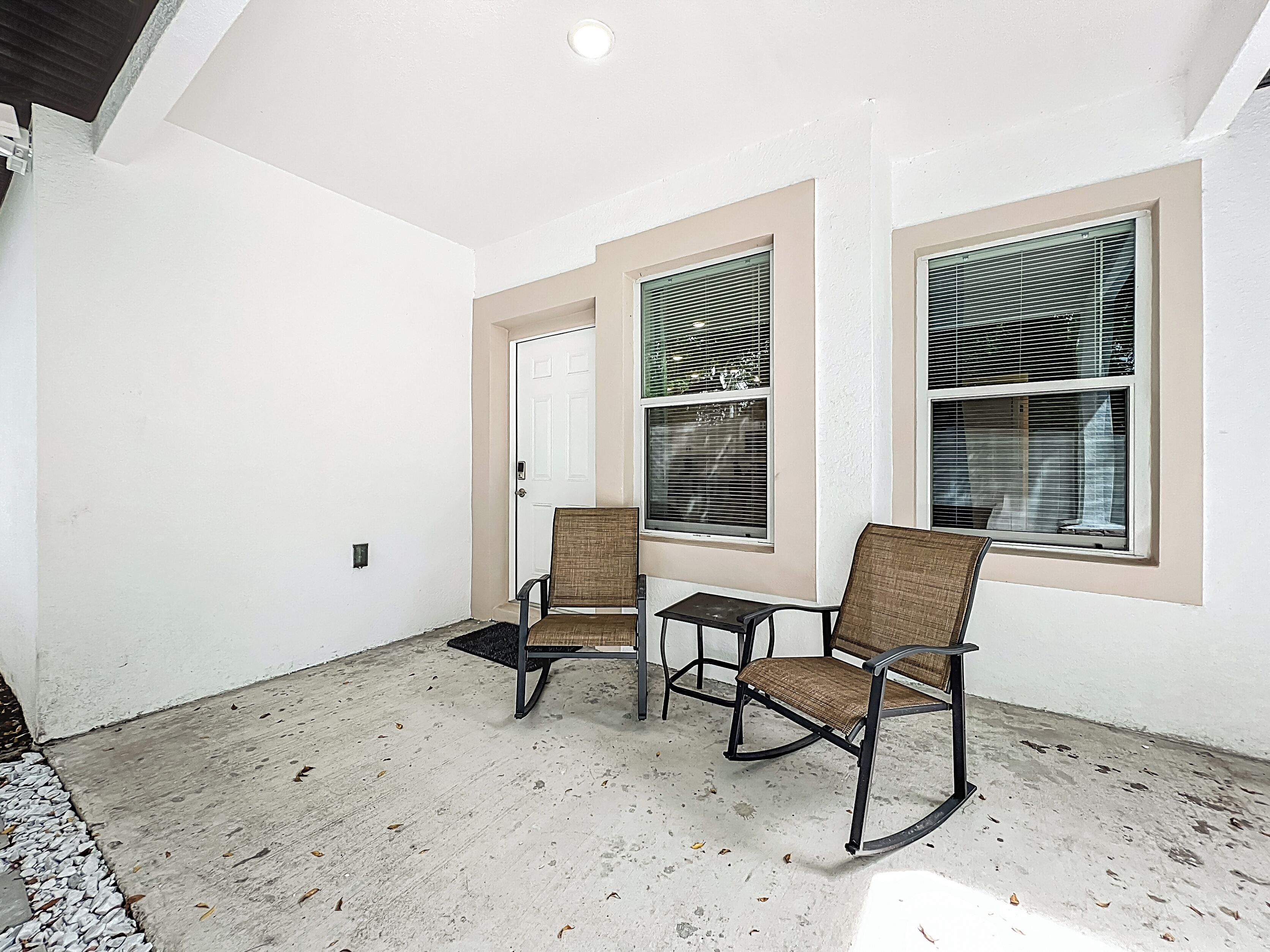 A room with two rocking chairs, a small table, and a door.