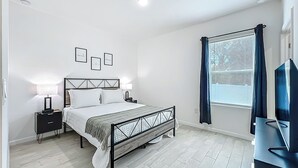 A modern bedroom with a bed, bedside tables, a TV, and a window with curtains. - Getaways, your way!
Spacious & Modern 3BR, 2BA (Sanford)