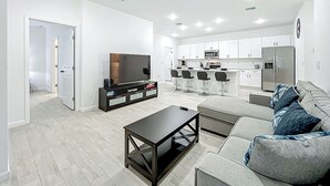 A modern living room with a TV, bar stools, and a sofa. - Getaways, your way!
Spacious & Modern 3BR, 2BA (Sanford)