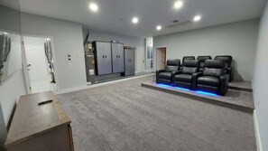 Une salle de cinéma privée avec un sol recouvert de moquette, un canapé et un projecteur fixé au plafond.