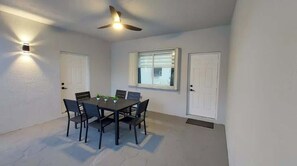 Una habitación con una mesa de comedor, sillas, un ventilador de techo y dos puertas.