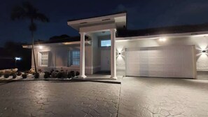 A modern house with a covered entryway, a garage, and a stone-paved driveway.