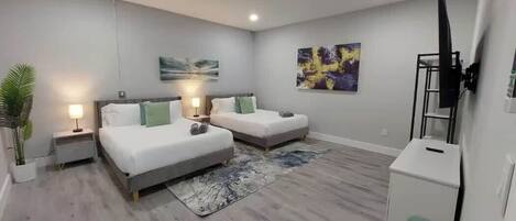 A hotel room with two beds, a TV, a desk, and a plant.