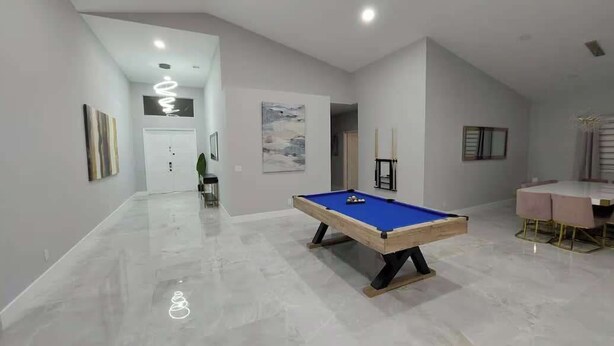 A modern room with a pool table, a dining area, and a hallway leading to another room. - 9BR/5BA/Pool/Jacuzzi/Theater/Mini Golf/Beach (Pompano Beach)