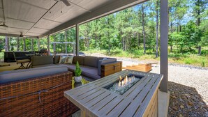 A covered outdoor seating area with a fire pit, a sofa, and a dining table. - Couples Escape w/ Hot Tub•Firepit •Trail Access (Broken Bow)