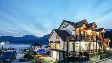 A two-story building with a balcony, a covered outdoor seating area, and a view of the water.