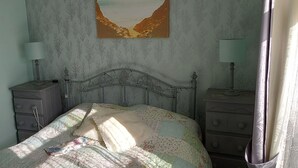 A bedroom with a bed, two nightstands, a dresser, and a mirror.