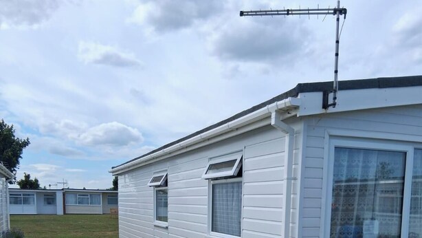 A row of white mobile homes with a grassy yard and a potted plant.