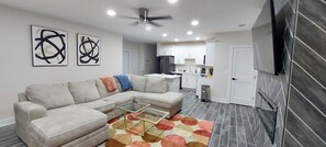 A modern living room with a sectional sofa, a glass coffee table, and abstract wall art.