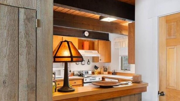 A kitchen with wooden cabinets, a stove, and a countertop. - Silver Moose Condo (Gallatin Gateway)