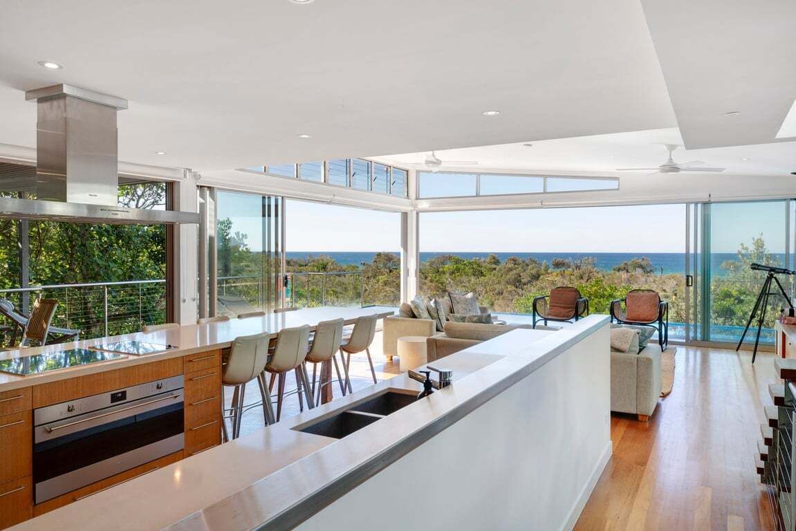 A modern kitchen with a large island, bar stools, and a view of the ocean.