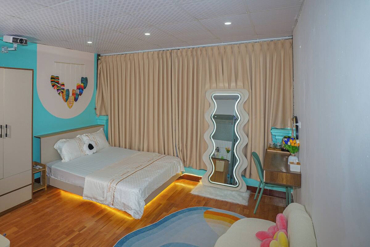 A bedroom with a bed, a mirror, a desk, and a chair.