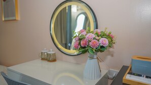A bathroom with a white sink, a mirror, a vase with pink flowers, a soap dispenser, and a tissue box. - Alula Ha Noi Homestay (Hanoi)