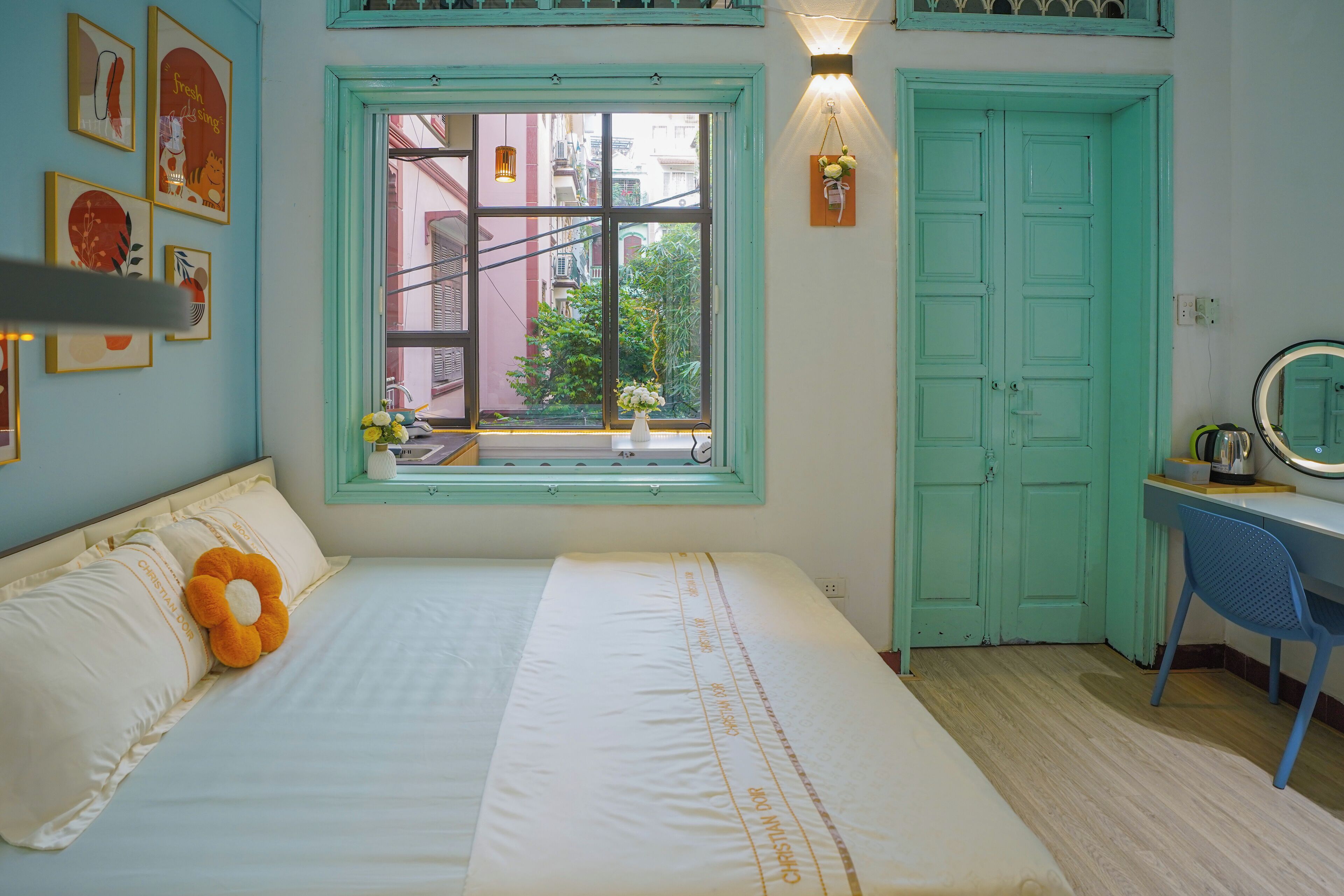 A bedroom with a bed, a desk, a window with a view, and a door.