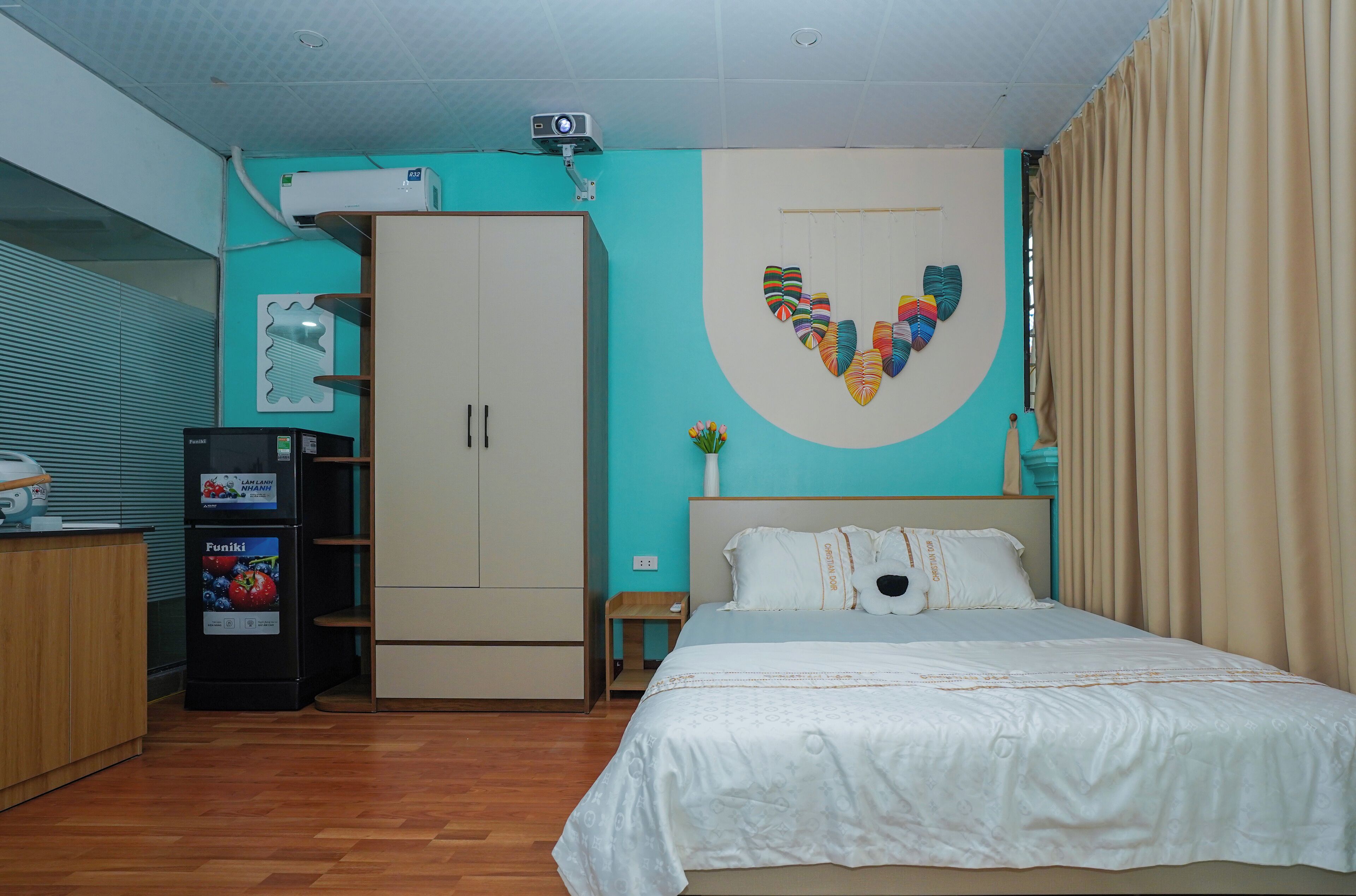 Un dormitorio con cama, armario, proyector y un adorno en la pared.