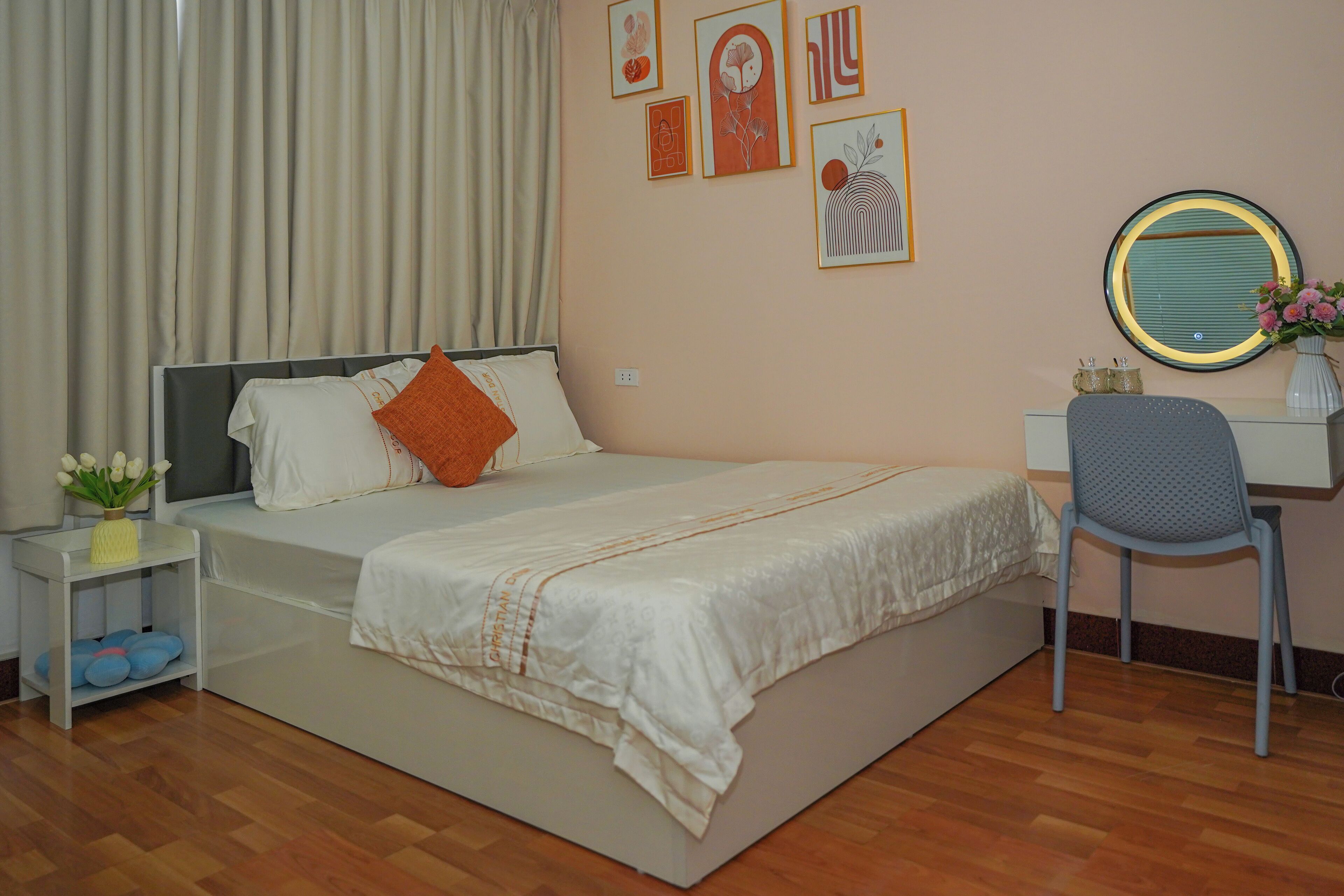 A bedroom with a bed, a desk, a chair, and a wall with framed pictures.