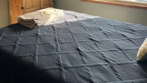 A bedroom with a bed, a wooden cabinet, a television, and a window with a view of a parking lot. - Kid-friendly cozy 2-bedroom, 2.5bath townhouse (Sioux Falls)