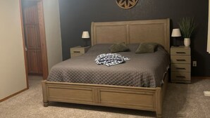 A bedroom with a bed, a ceiling fan, a wall clock, a nightstand, a drawer unit, and a door. - Kid-friendly cozy 2-bedroom, 2.5bath townhouse (Sioux Falls)