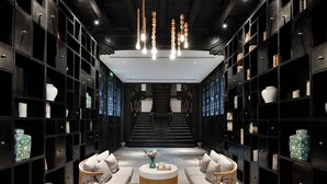 A modern interior with black shelving units, a central round coffee table, and a staircase leading to an upper level. - Blssom House Nanxun Huzhou  (Huzhou)