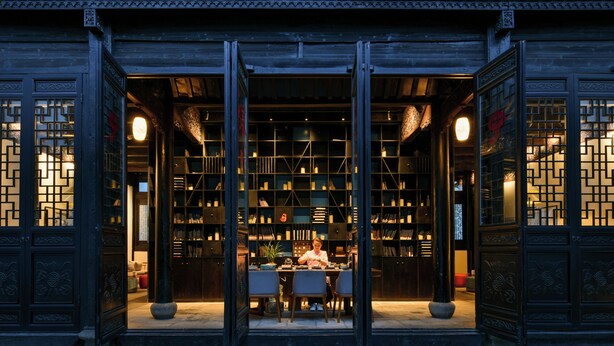A traditional building with a central open space featuring a table and chairs, surrounded by bookshelves. - Blssom House Nanxun Huzhou  (Huzhou)