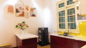 Eine kleine Küche mit weißem Arbeitsplatz, einem schwarzen Kühlschrank und einem Fenster mit grünen Vorhängen.