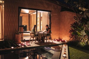 An outdoor dining area with a glass table, chairs, and a view into the interior of a building. - Terra Sayan (Ubud)
