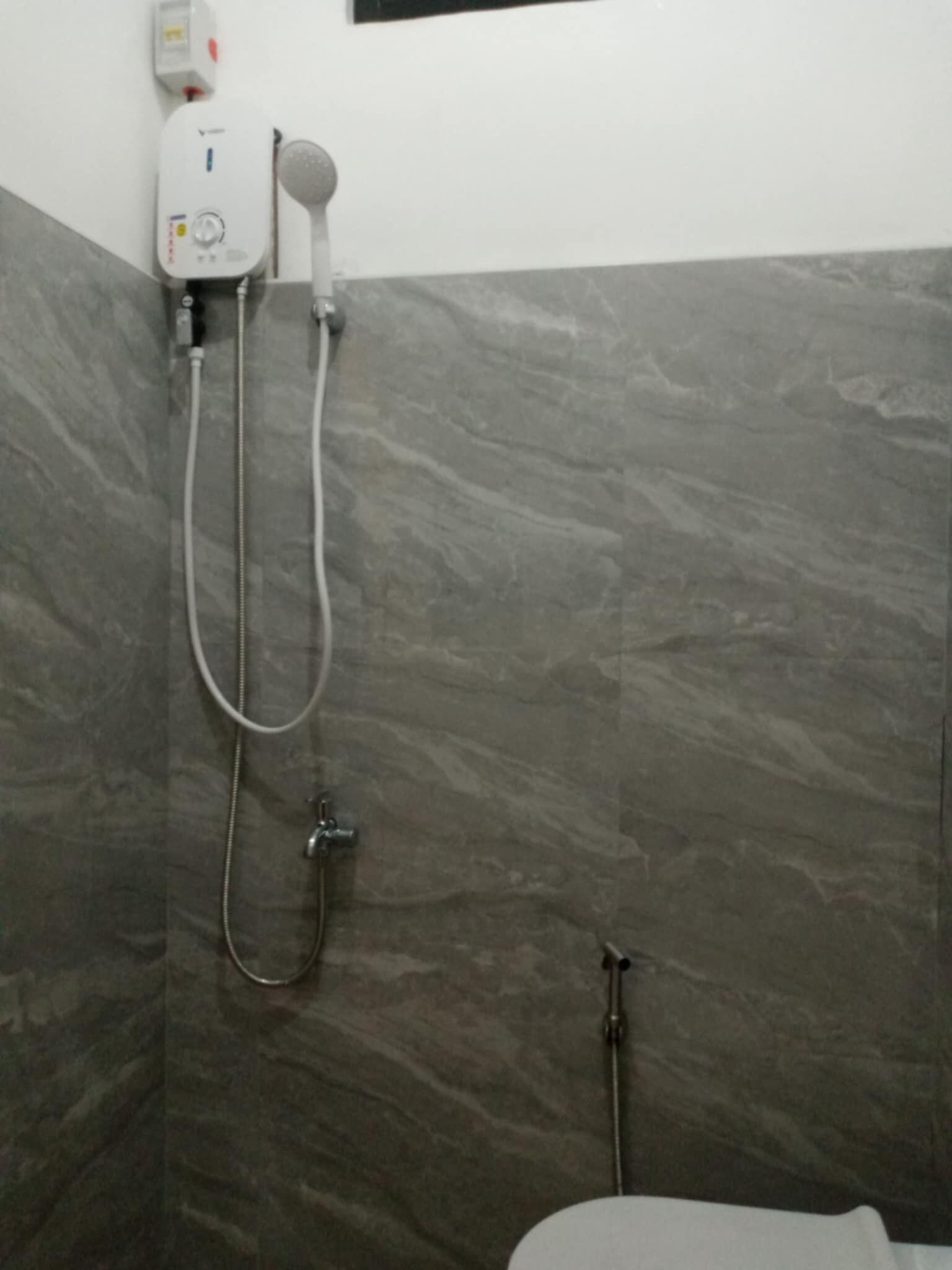 A bathroom with a shower, a toilet, and a wall-mounted water heater.