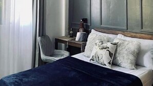 Ein modernes Hotelzimmer mit einem großen Bett, einem Nachttisch mit Lampe und einem Sessel.