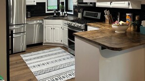 Una cocina moderna con armarios blancos, electrodomésticos de acero inoxidable y encimera de madera.