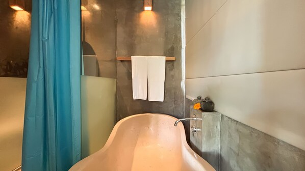 A bathroom with a bathtub, a towel rack with a towel, and a small decorative item on the wall.