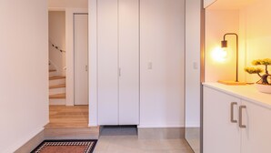 A hallway with a staircase, a white wardrobe, and a lit lamp with a plant.