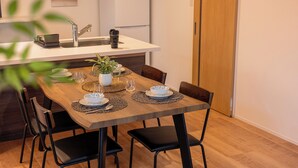 A dining area with a wooden table, black chairs, and a kitchen in the background.