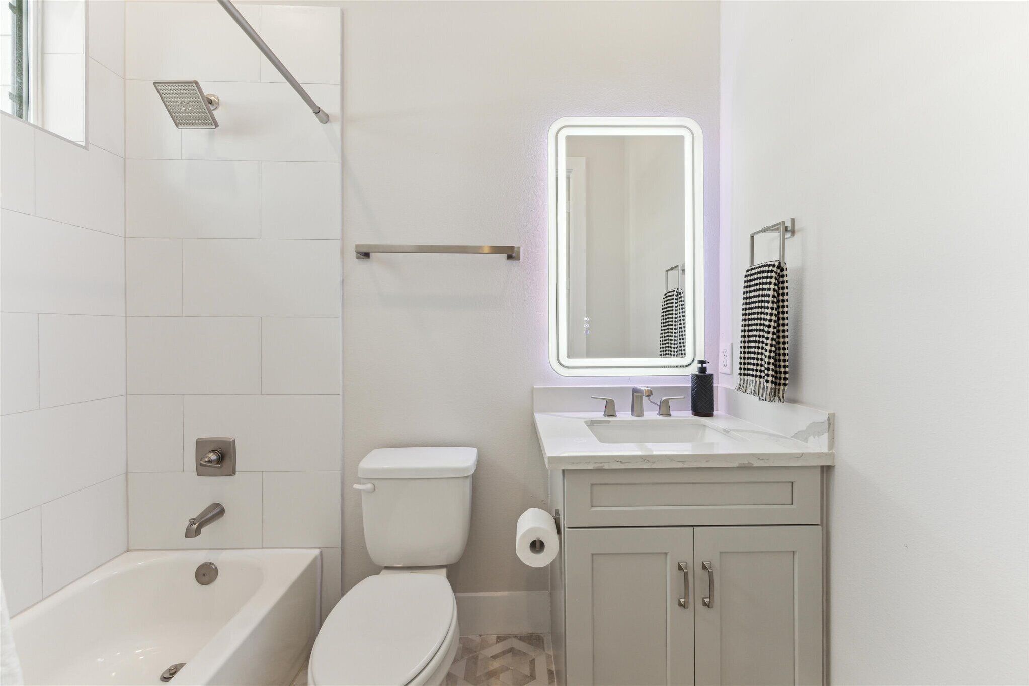 A modern bathroom with a bathtub, toilet, and vanity.