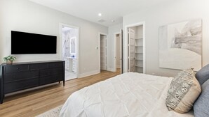 A bedroom with a bed, a dresser, a TV, and a closet.