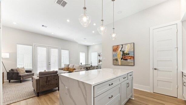 A spacious living area with a large island, a dining table, and a sofa.