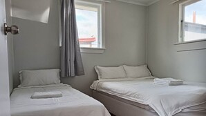 Un dormitorio con dos camas individuales, una ventana con cortinas y una puerta.