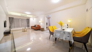 Een moderne eetruimte met een marmeren tafel, gele stoelen en een bank op de achtergrond.